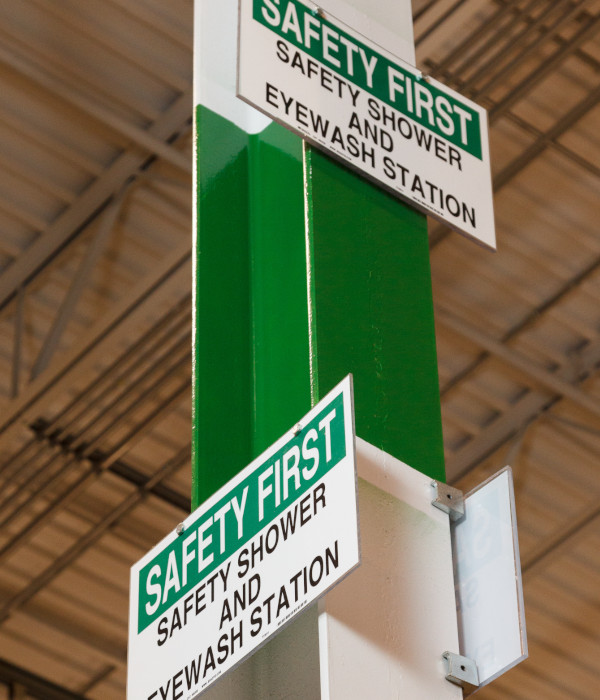 Two eyewash station signs on a pillar.