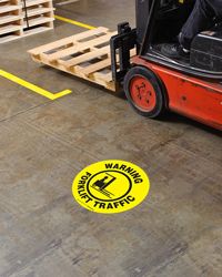 Yellow circles and floor marking tape in warehouse setting.