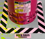 Red drum surrounded by yellow and black striped floor tape and labeled as used rags flammable.