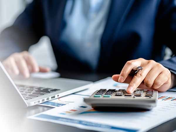 A business person sits at her desk and pushes buttons on calculator.