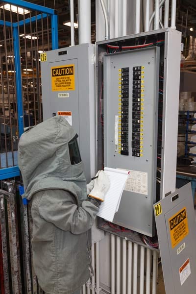 Inspecting an electrical panel for arc flash risk.