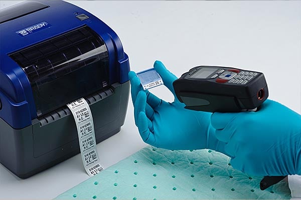 Lab tech labels a sample after using a Brady thermal transfer printer. 