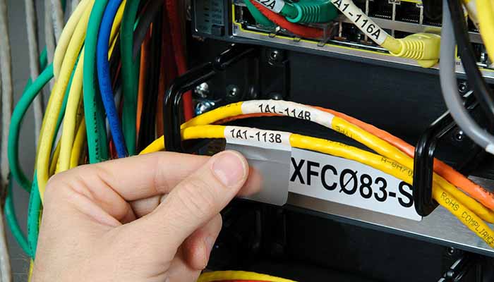 Closeup of a worker attaching a coded label to a small cable. 