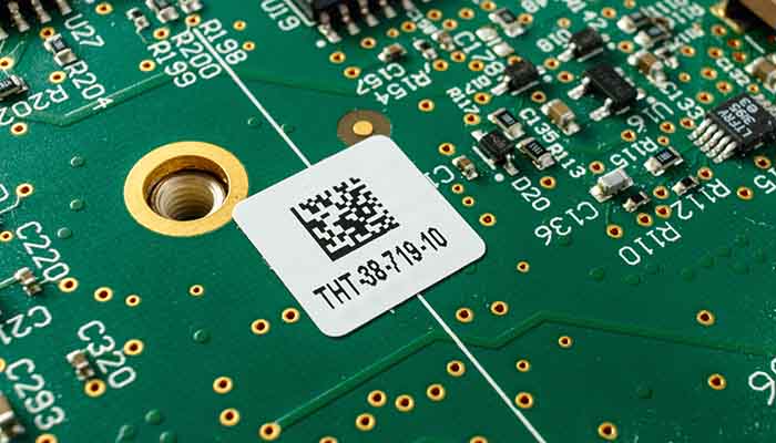 Closeup of a circuit board with a white barcode label.