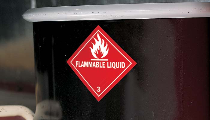 A black drum with a red diamond-shaped flammable liquid warning label. 