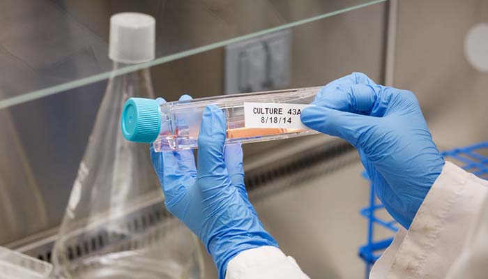 Closeup of a lab tech placing a label on a large vial. 