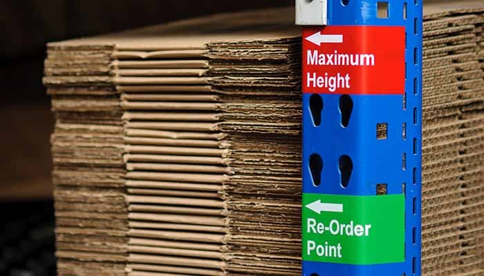 Labels on a pole indicating maximum stacking height for folded boxes.