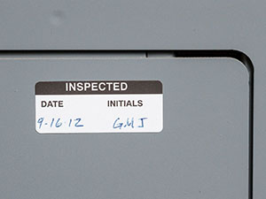 Grey industrial box with &quot;inspected&quot; label and handwritten dates.