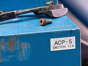 Closeup of a blue metallic object with label and tools on top.