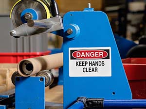 Blue industrial equipment with &quot;Danger keep hands clear&quot; label. 