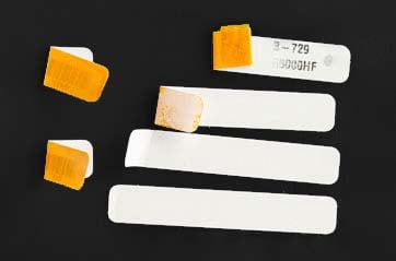 Partically peeled white labels on a black surface. 