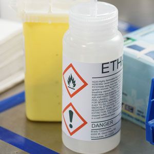 Closeup of two small plastic containers with GHS labels. 