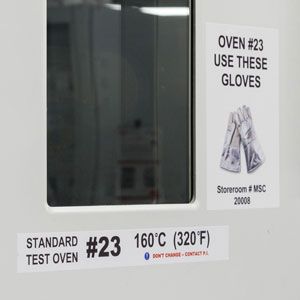 Closeup of a lab oven with warning signs next to it. 