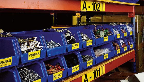 Several blue plastic bins in a warehouse holding items.