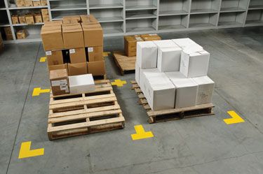 Some pallets sit within yellow Brady floor marking tape.