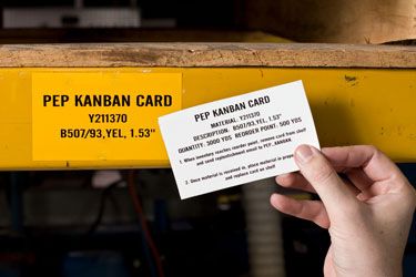 Closeup of a Brady Kanban card next to a yellow industrial shelf.