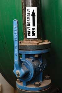 Closeup of a blue valve with a Brady pipe marking arrow label. 