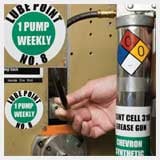 Closeup of a grease gun with warning signs.