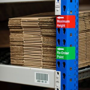  A blue pole with colored labels indicating maximum level of stacked boxes. 