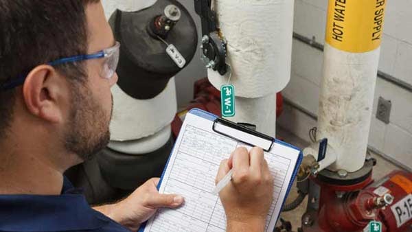Worker performs a LOTO procedure check on a hot water supply pump.