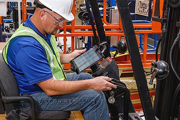 Forklift driver referencing OSHA compliance