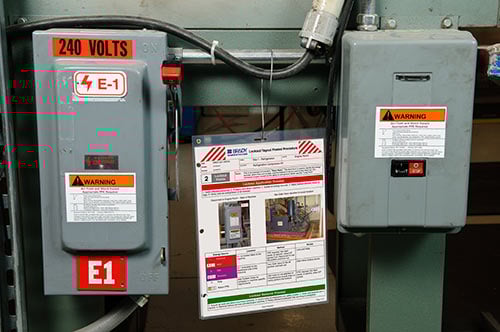 Two electrical boxes with warning labels and a LOTO document. 
