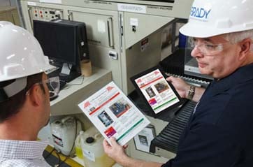 Two workers in hardhats review LOTO procedure documents.