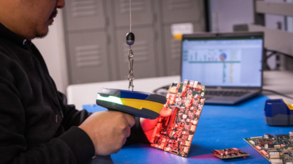 Person scanning a barcode on a circuit board.