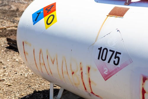 A propane tank with flammable warning labels.