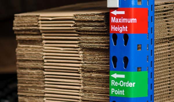 A metal pole with labels indicating maximum height of stacked boxes.