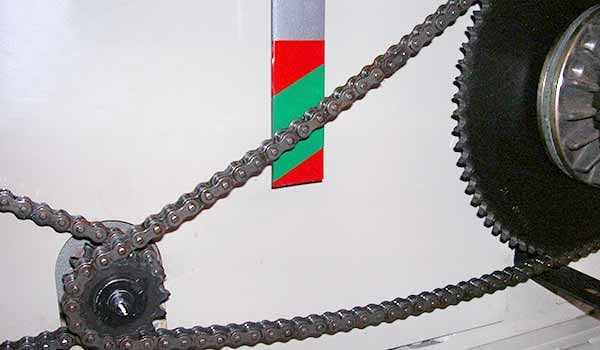 Closeup of a chain wrapped around two sprockets.