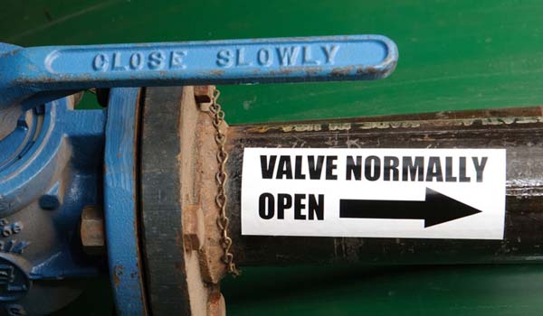 Industrial valve next to an arrow sticker indicating open direction.