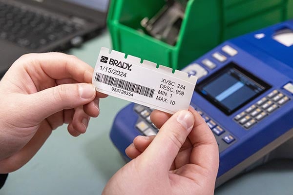 Hands holding a label printed on a Brady printer.