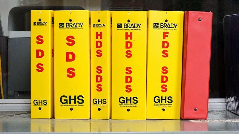 A group of yellow Brady safety data sheet binders.