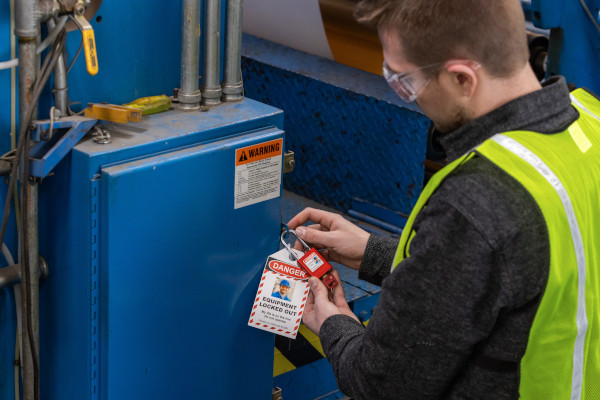 Person in a yellow safety vest auditing lockout tagout procedure.