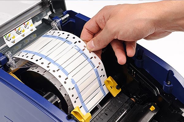 Hand loading labels into a label printer.