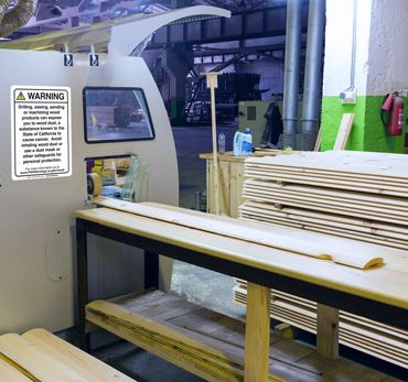 Proposition 65 warning sign in an industrial woodworking area.