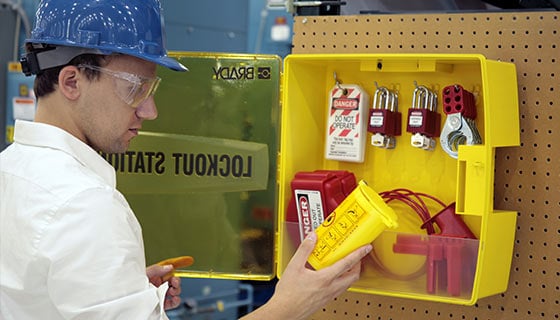 Worker accesses LOTO equipment in a yellow storage box.