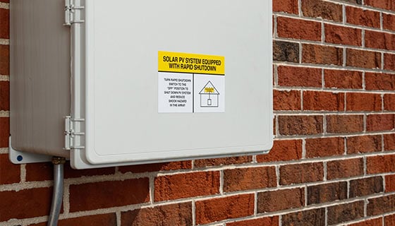 Closeup of a solar power rapid shutdown box on a brick wall.