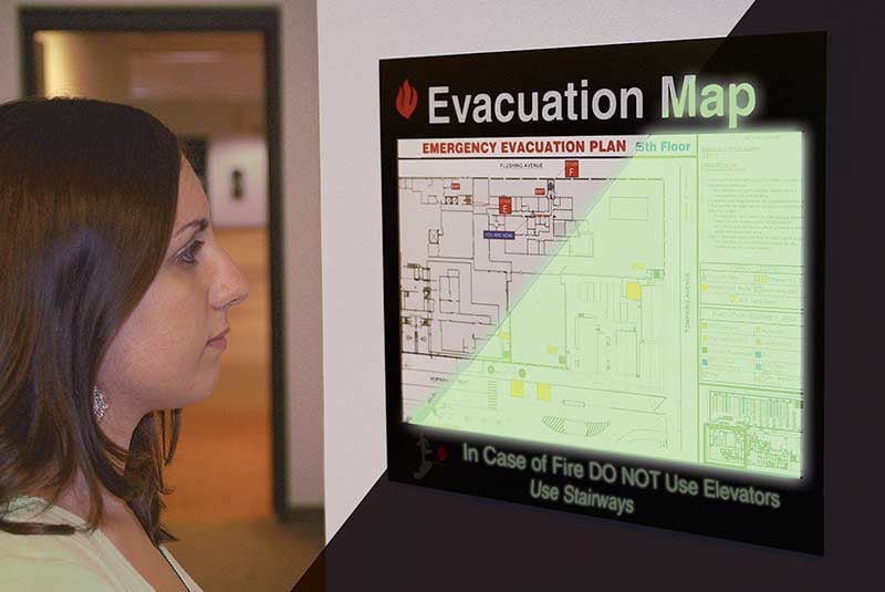 Employee looks on at a glowing evacuation map display.