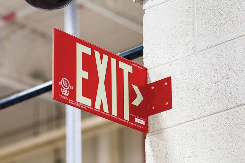 A red exit sign on the corner of a wall.