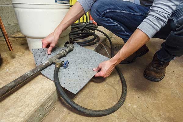 An employee using TAA-compliant Brady absorbant pad