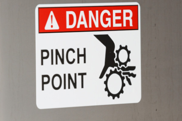 A sign warning of a machine's pinch point.