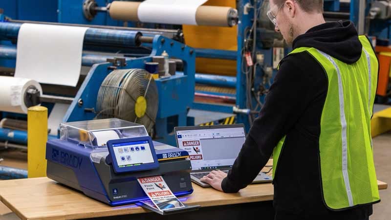 Man in safety vest prints labels on a Brady printer.