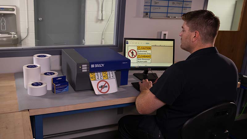 A man uses a BradyJet J4000 label printer at a computer.