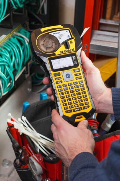 Datacomm worker using a Brady M210 Printer to label cables.