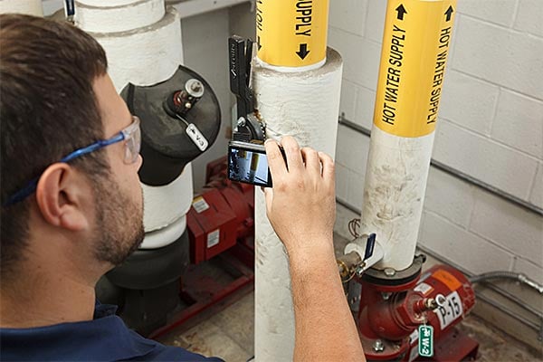 Employee inspecting a hot water supply pipe.