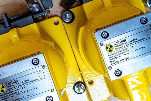 Close-up of equipment parts with radioactive metal plate warnings.