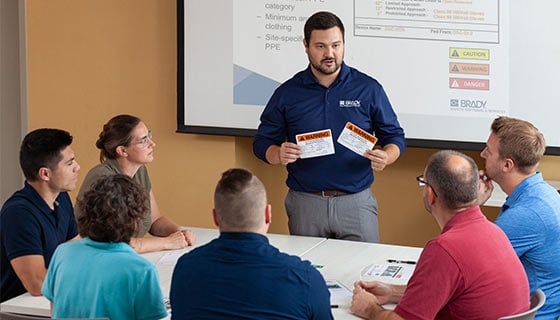 Trainer holds warning labels while instructing students.