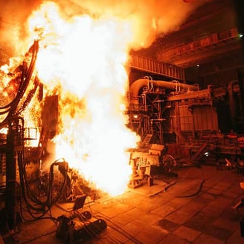 Fire in an industrial setting with machinery and pipes visible.